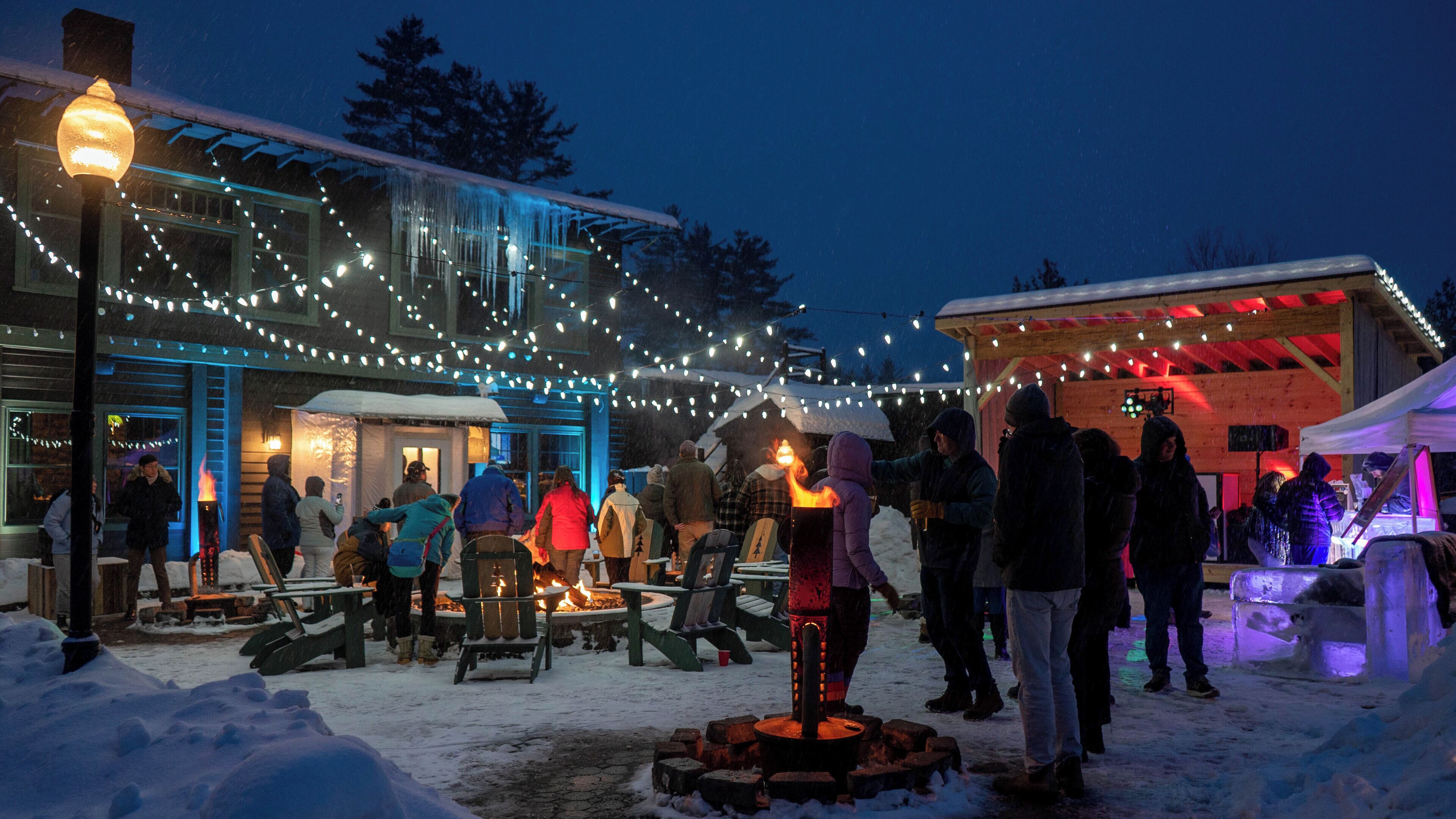 A snow-covered outdoor area with string lights and a fire pit.