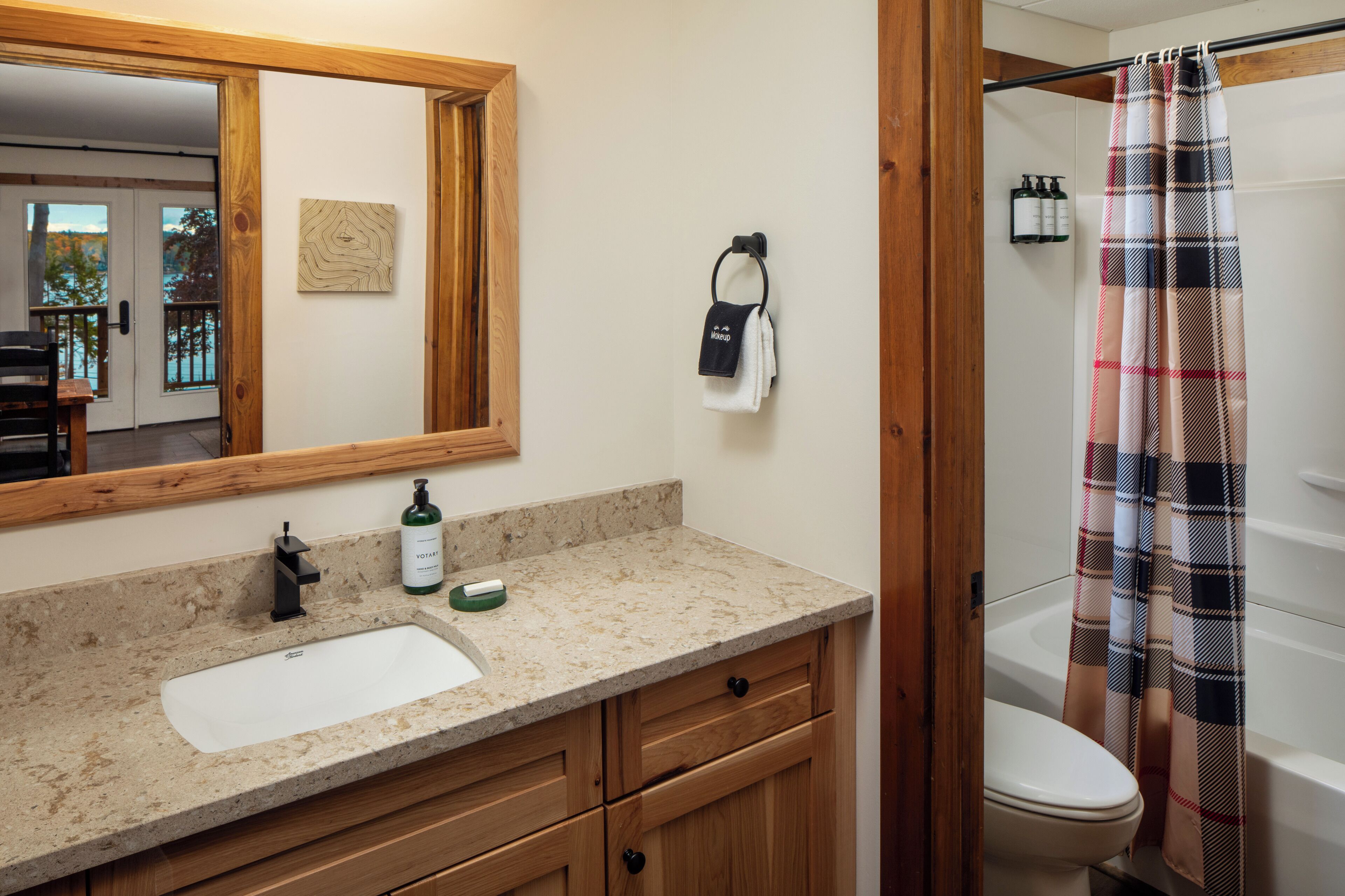 A bathroom with a wooden vanity, a sink, a mirror, a towel rack, and a shower curtain.