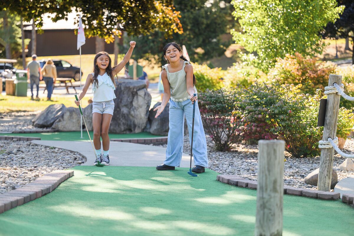 Un campo de mini golf con superficie de césped verde, postes de madera y una bandera.