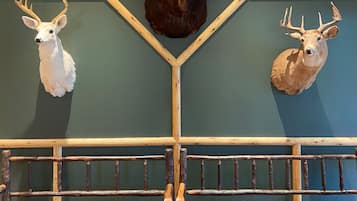 A room with a wooden bench, a wall-mounted deer head, and a wooden rack.