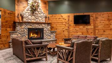 A cozy room with a stone fireplace, wooden walls, and rustic furniture.
