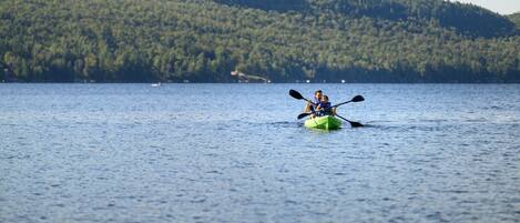 A kayak on a calm lake with a forested hill in the background.