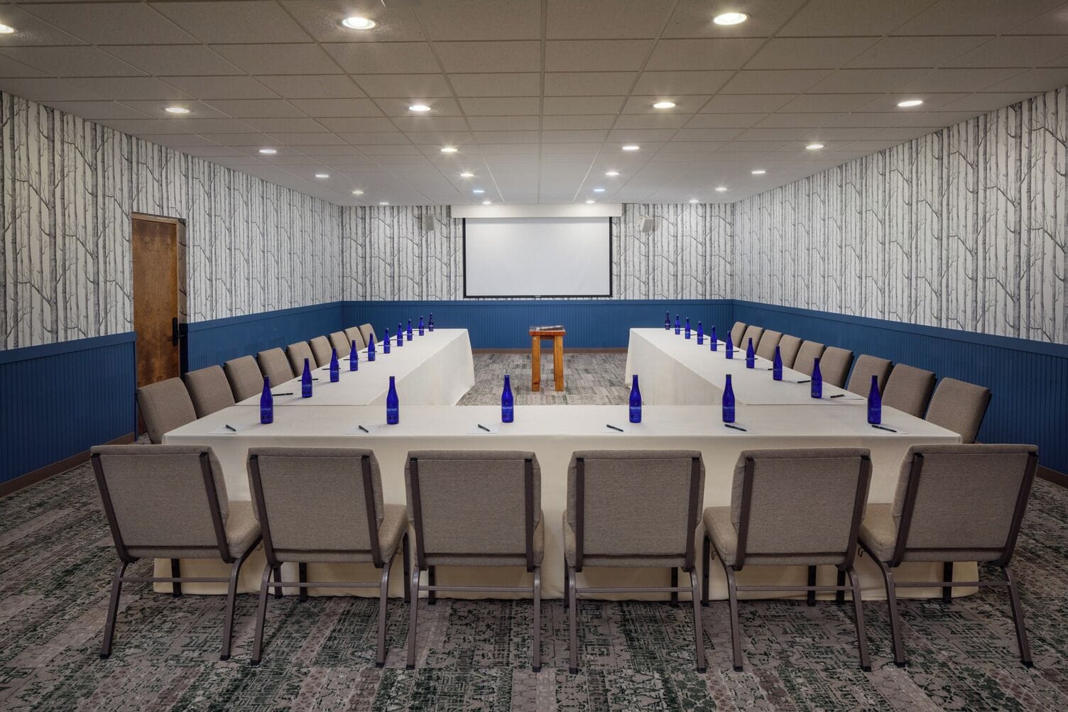 A conference room with a long table, chairs, and a podium.
