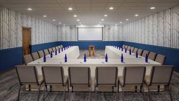 A conference room with a long table, chairs, and a podium.