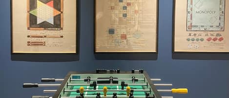 Une pièce avec une table de baby-foot et des reproductions encadrées de dessins de brevets accrochées au mur.