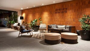 Un hall d’entrée moderne avec un mur en bois, un espace salon et des plantes en pot.