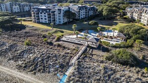 An aerial view of a residential complex with multiple apartment buildings, a playground, and a swimming pool. - Sunset Rentals | Island Club 114 (Hilton Head Island)