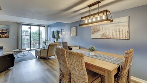 A dining area with a wooden table, woven chairs, and a hanging light fixture. - Sunset Rentals | Island Club 114 (Hilton Head Island)