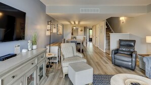 A modern living room with a TV, seating, and a staircase. - Sunset Rentals | Island Club 114 (Hilton Head Island)