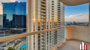 A high-rise building with a balcony overlooking a cityscape, including a Hilton Grand Vacations hotel and a pool area. - MGM Signature- F1 Track Jacuzzi Strip View Balcony (Las Vegas)