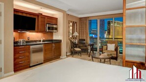 A hotel room with a kitchenette, a dining area, and a large window with a city view. - MGM Signature- F1 Track Jacuzzi Strip View Balcony (Las Vegas)