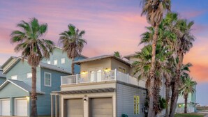 A two-story house with a balcony, garage, and palm trees. - The almost seamless integration of outside and inside makes this the picture-per (Port Aransas)