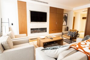 Una sala de estar moderna con sofá, mesa de centro, televisor y chimenea.