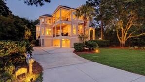 A two-story house with a covered front porch, a driveway, and a well-maintained lawn. - 12 Port Tack -  4 min walk to the ocean.  Views of golf, lagoons & sunset (Hilton Head Island)