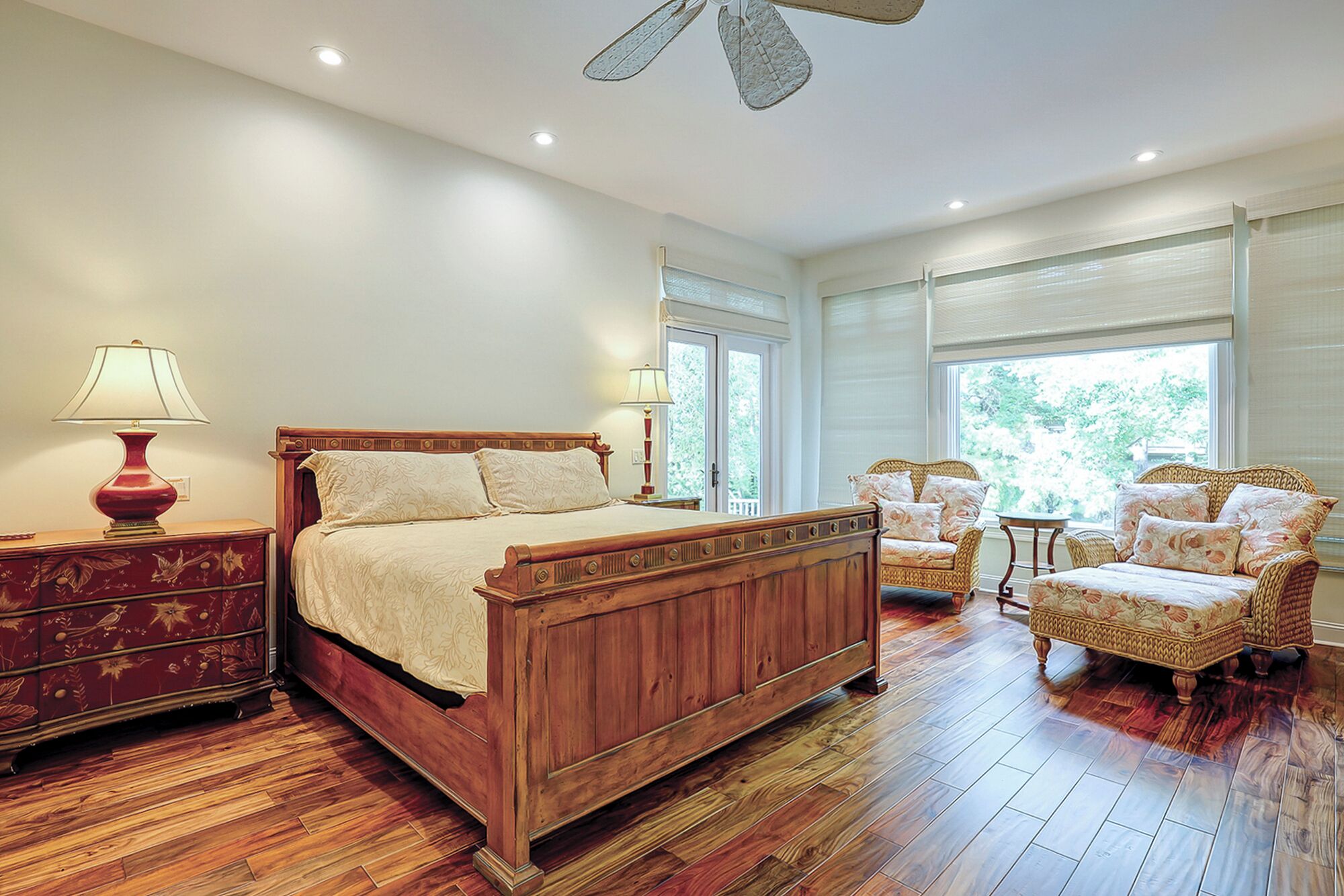 A bedroom with a wooden bed, two chairs, a nightstand, and a dresser.