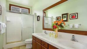 Une salle de bain avec deux lavabos, des toilettes, une douche et un grand miroir.