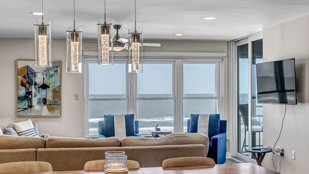 Un salon moderne avec un grand canapé, une table à manger avec de l’assiette et un téléviseur fixé au mur.
