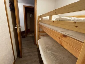 Un letto a castello in una stanza con pavimento in legno e pareti bianche.