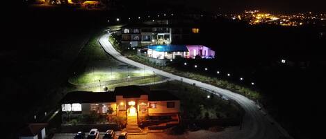 Vista nocturna de un edificio con estacionamiento y una carretera que lleva a él.