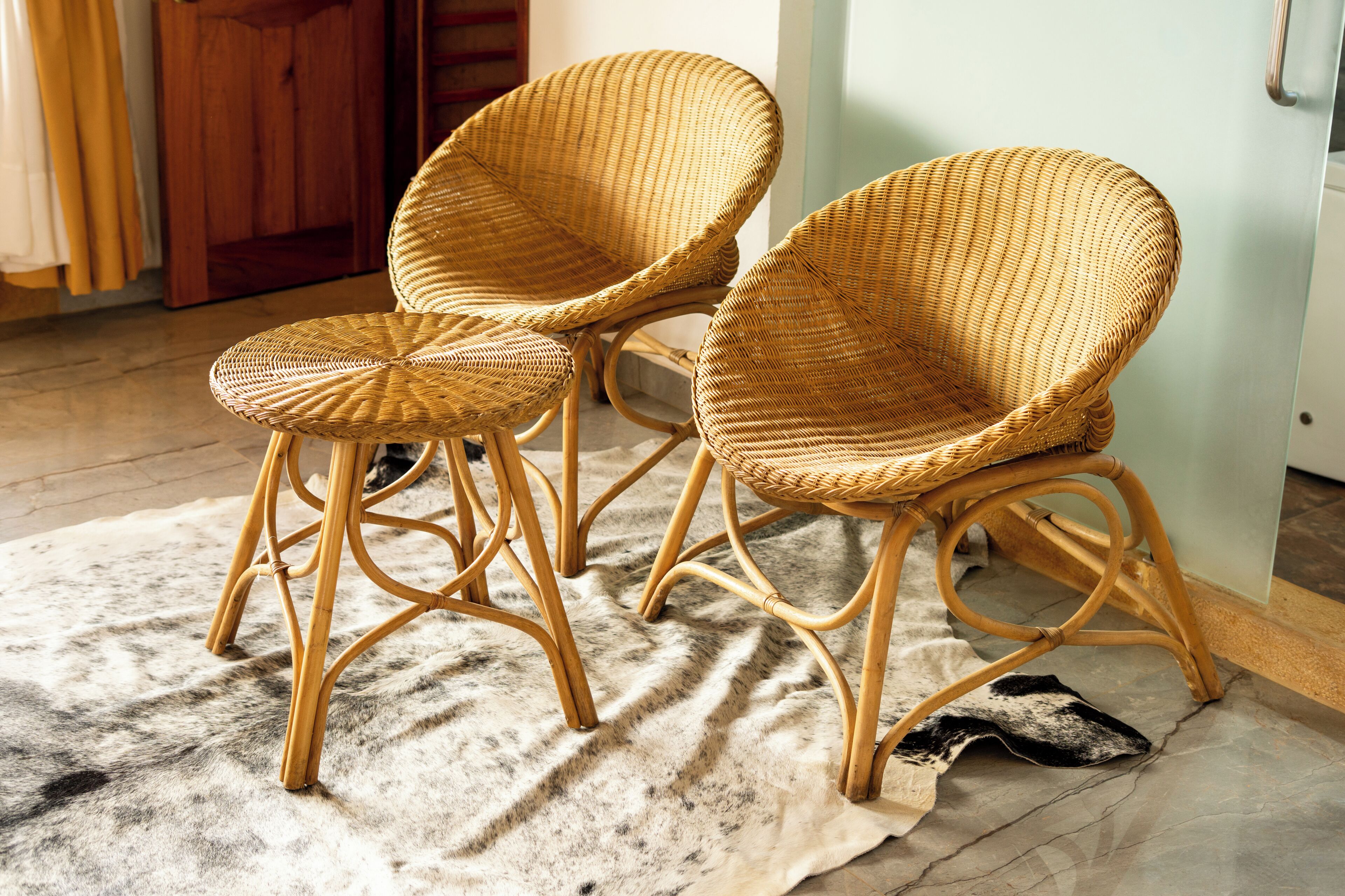 Deux chaises en osier avec des pieds en métal, posées sur un tapis à motifs.