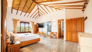 A bedroom with a bed, wooden furniture, a TV, and a view through the window. - Hotel Cordillera de los Andes  (Villa de Leyva)