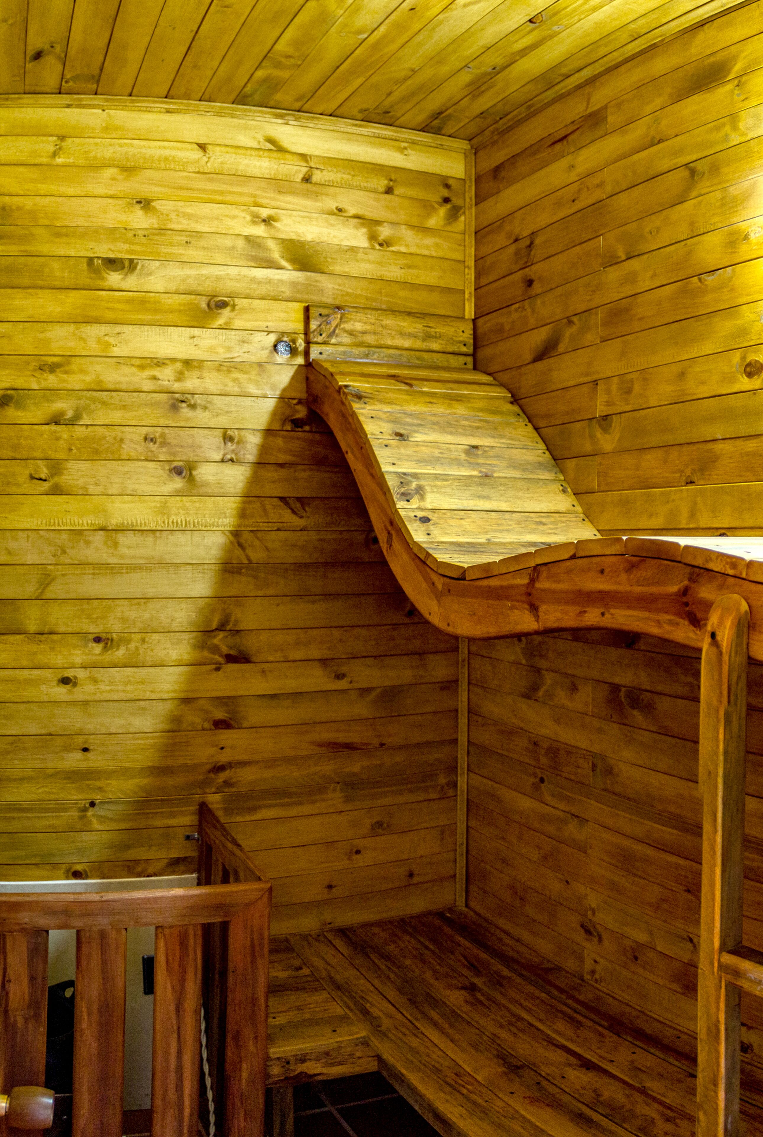 A wooden interior with a sloped ceiling and a wooden bench.