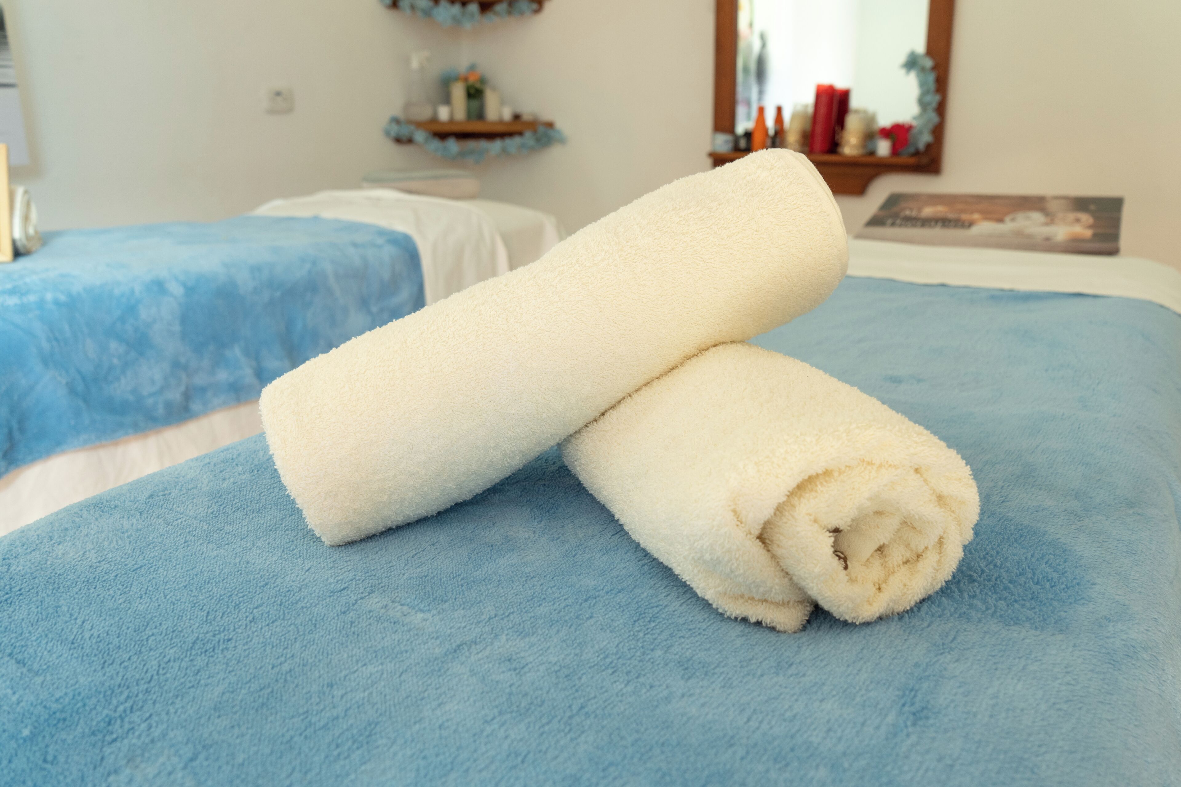 Un letto con una coperta blu e due asciugamani bianchi.