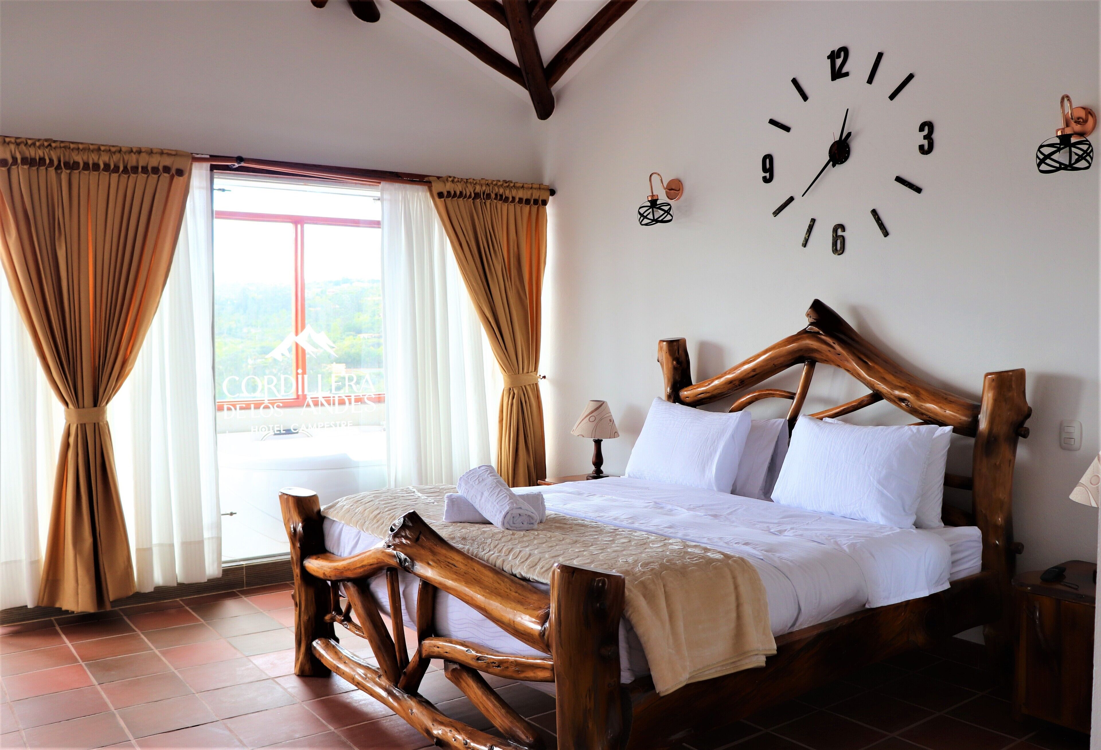 A wooden bed with a headboard, a wall clock, and curtains.