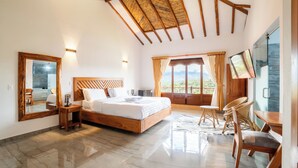 A spacious bedroom with a large bed, a wooden ceiling, a TV, and a balcony with a view. - Hotel Cordillera de los Andes  (Villa de Leyva)