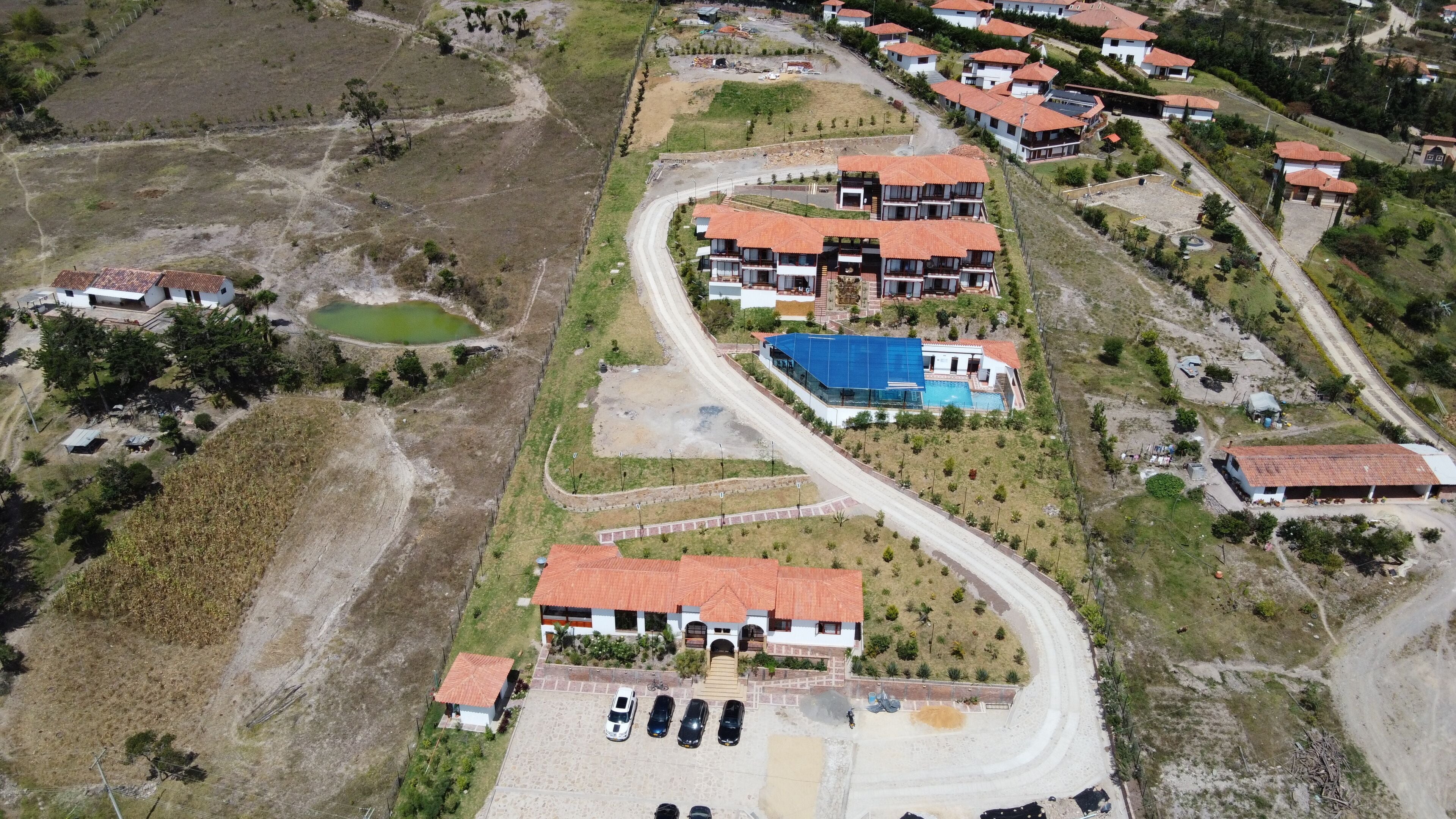 Vista aérea de una zona residencial con casas, piscina y estacionamiento.