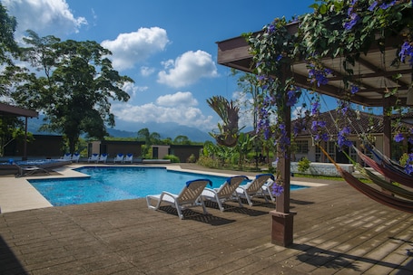 Una piscina al aire libre, sillones reclinables de piscina