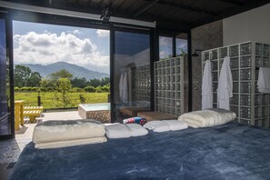A bedroom with a large bed, a bench, and a view of mountains through a glass door.