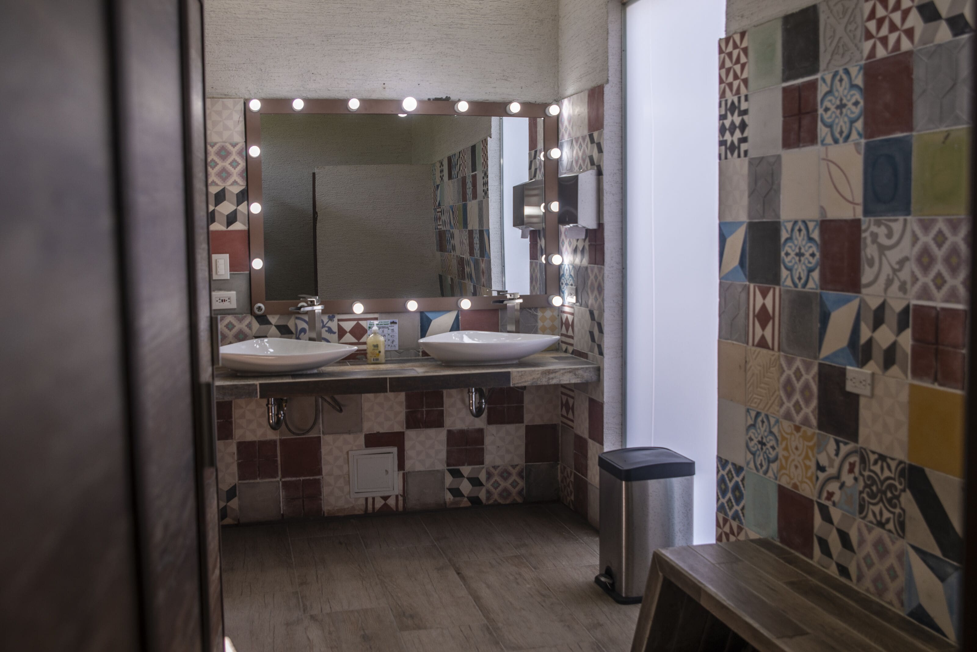 Une salle de bain avec deux lavabos, un miroir avec éclairage intégré et un mur recouvert de carreaux.
