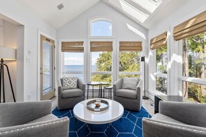 A modern room with a large window, two sofas, a coffee table, and a lamp.