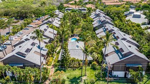 Zona residencial con varias casas, piscina y palmeras.
