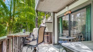 Un patio al aire libre con una mesa y sillas, rodeado de abundante vegetación.