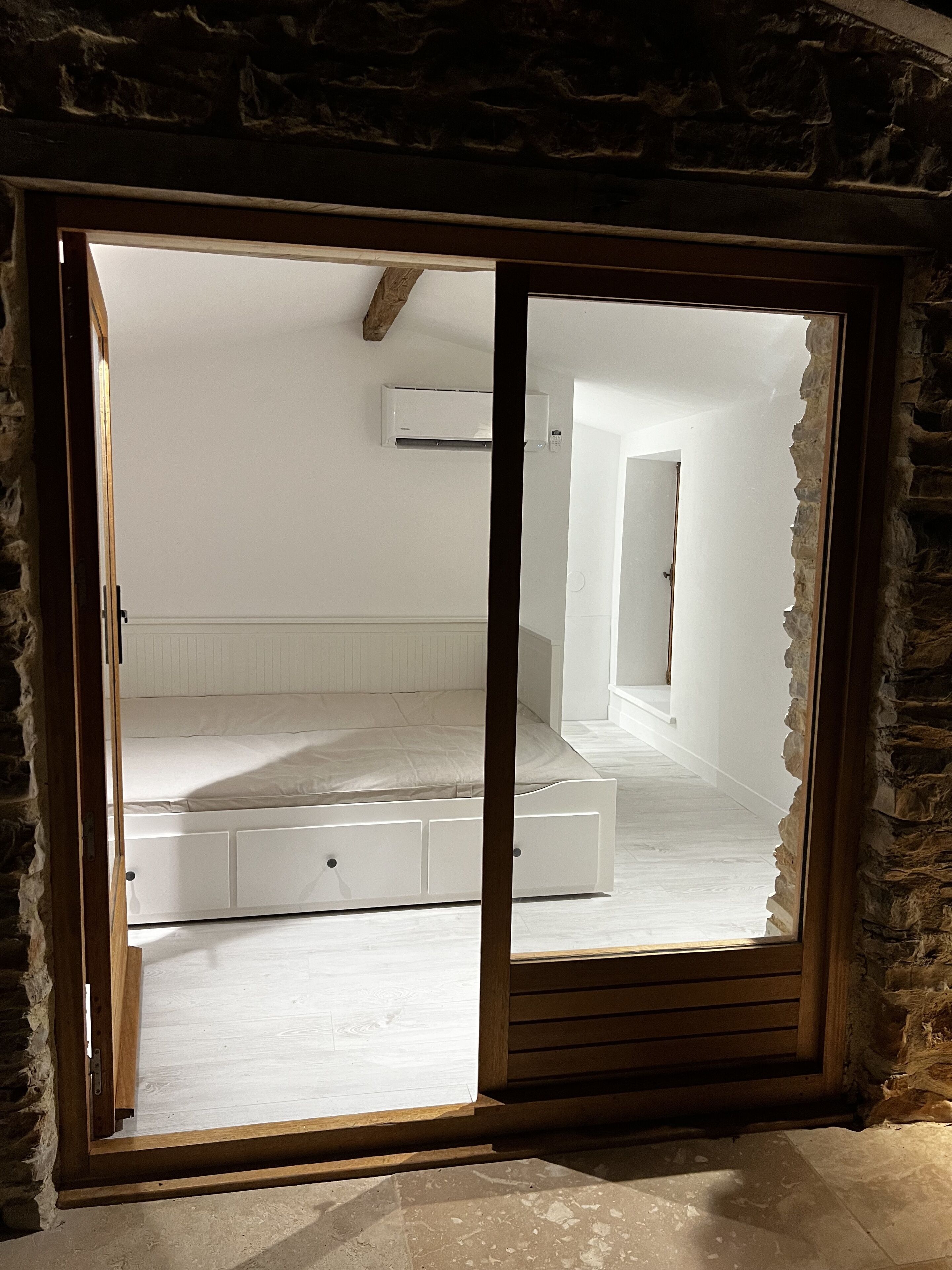 Une chambre avec un lit intégré, un mur en pierre et un plafond blanc.