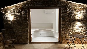 Ein Steinhaus mit Bett und Stuhl vor der Tür.