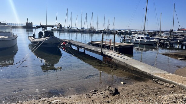 Een jachthaven met aangemeerde boten, een betonnen steiger en rustig water.
