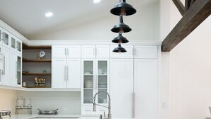 Une cuisine moderne avec des meubles blancs, un îlot central et un coin bar.
