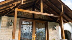 Un bâtiment doté d’un porche en bois, de murs en pierre et d’une grande porte en bois ornée de panneaux de verre décoratifs.