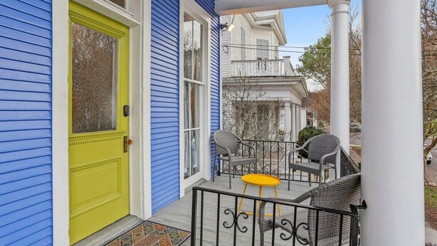 Une véranda avec une porte jaune, un revêtement bleu et une petite table entourée de chaises.