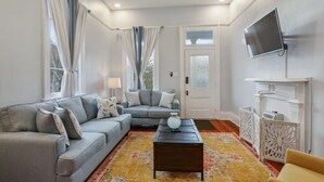 Un salon avec un canapé gris, une table basse, un téléviseur fixé au mur et une cheminée.