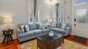 Un salon avec deux canapés gris, une table basse et deux lampes.