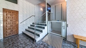 Eine Marmorboden-Treppe mit Handlauf, einer Holztür und einer Bank.