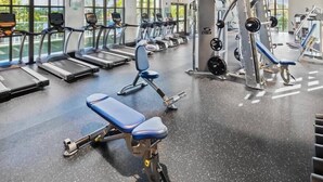 A gym with treadmills, weight machines, and benches. - Escape to Our Beautiful and Comfy Home at Solara (Kissimmee)