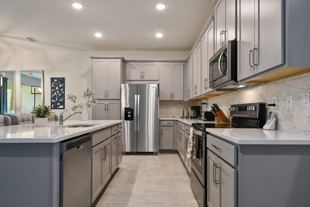 A modern kitchen with stainless steel appliances, grey cabinetry, and a central island.