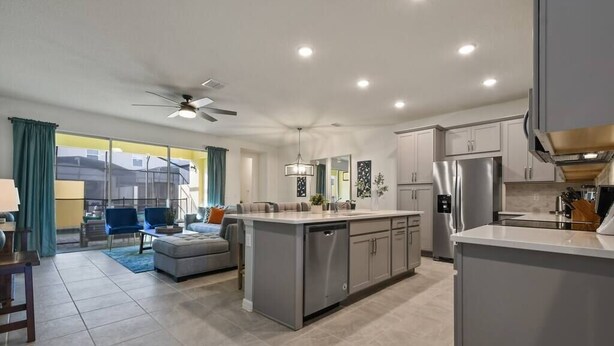 A modern kitchen with a central island, built-in appliances, and a dining area with a view. - Escape to Our Beautiful and Comfy Home at Solara (Kissimmee)