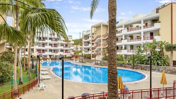 Ein Resort mit Swimmingpool, Palmen und mehrstöckigen Gebäuden mit Balkonen.