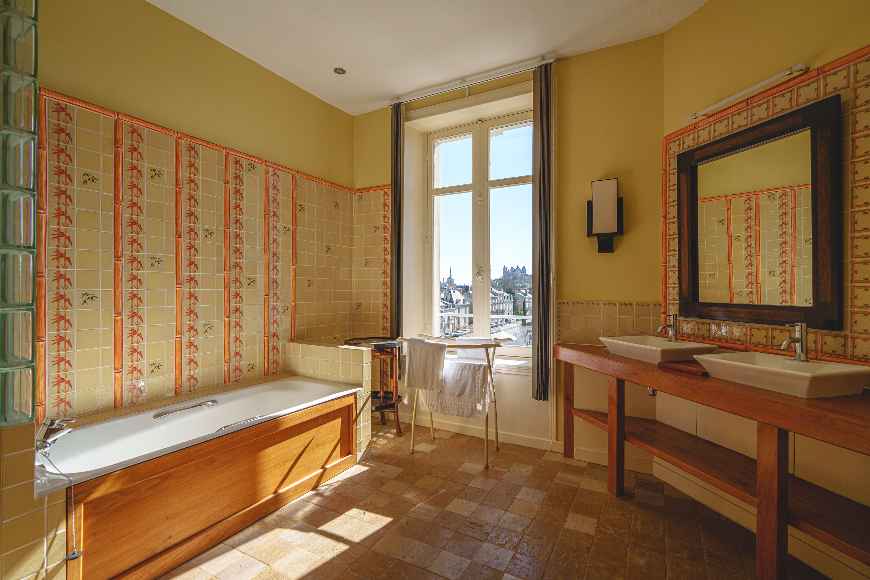 A bathroom with a bathtub, two sinks, and a large window.